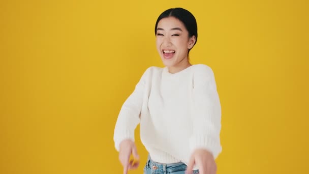 Una Mujer Asiática Sonriente Señala Cámara Pie Aislada Sobre Una — Vídeo de stock