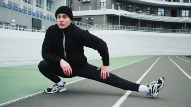 Приємний Молодий Спортсмен Готується Перед Бігом Марафону Розтягуючи Ноги Стадіоні — стокове відео