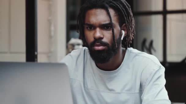 Ein Ernsthafter Afrikanisch Amerikanischer Mann Mit Ohrhörern Benutzt Seinen Laptop — Stockvideo