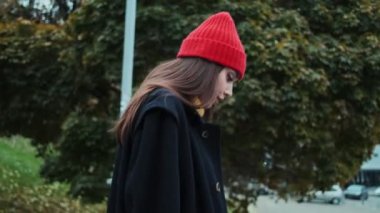 Gülümseyen bir kadın sokakta palto ve şapkayla merdivenlerden iniyor.