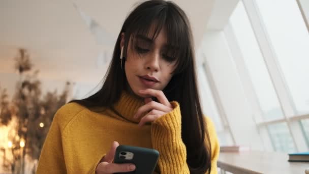 Una Mujer Pensativa Con Auriculares Pensando Algo Luego Mirando Teléfono — Vídeo de stock