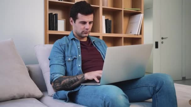Hombre Enfocado Está Usando Computadora Portátil Mientras Está Sentado Sofá — Vídeo de stock