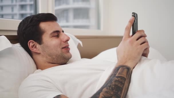 Zadowolony Człowiek Używa Rano Swojego Smartfona Leżącego Złym Miejscu — Wideo stockowe