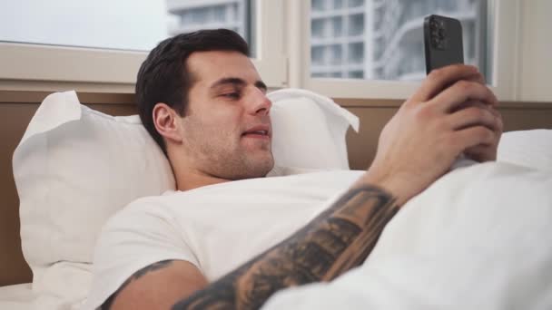 Uśmiechnięty Mężczyzna Używa Rano Swojego Smartfona Leżącego Złym Miejscu — Wideo stockowe