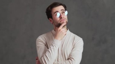 Gözlüklü dalgın bir adam stüdyoda ellerini açarken olumsuz bir şekilde başını sallamayı düşünüyor.