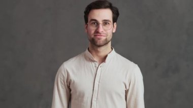 Stüdyoda ellerini çırparken zafere sevinen gözlüklü mutlu bir adam.