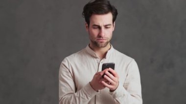 Yoğunlaşmış bir adam stüdyoda elinde tutarken telefonla kötü niyetli bir şekilde daktilo çekiyor.