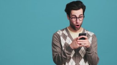 Kameranın sağında duran şaşırmış adam stüdyoda telefonu elinde tutarken mesaj atıyor.