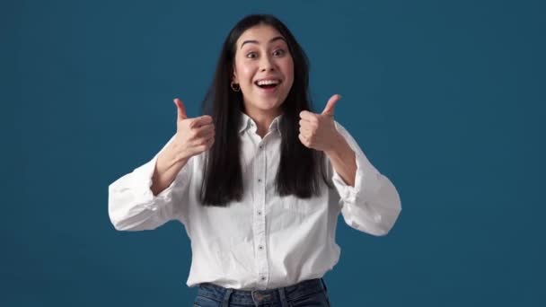 Een Gelukkige Koreaanse Vrouw Toont Duim Omhoog Gebaar Geïsoleerd Blauwe — Stockvideo