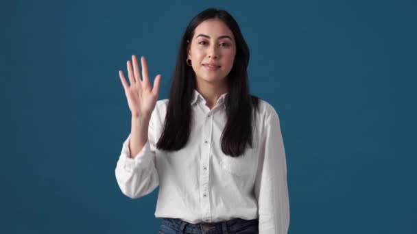 Gülümseyen Koreli Bir Kadın Sallıyor Stüdyoda Mavi Duvarın Üzerinde Durmuş — Stok video