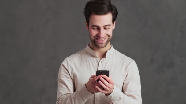 Hombre Sonriente Mirando Teléfono Mientras Sostiene Sus Manos Estudio — Vídeos de Stock