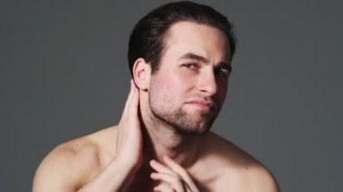 Memnun bir adam, stüdyodaki gri duvarın arkasında duran saç stiline bakıyor.