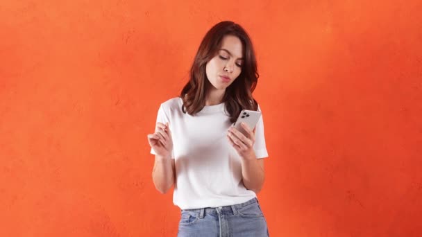 Zamyšlená Žena Přemýšlí Napsat Zatímco Drží Telefon Rukou Oranžovém Studiu — Stock video