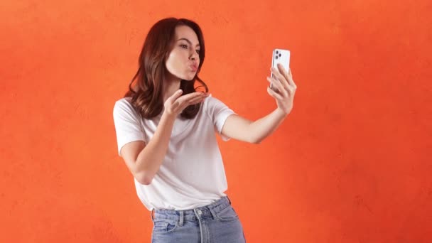 Uśmiechnięta Kobieta Robi Sobie Selfie Przez Telefon Pozuje Pomarańczowym Studio — Wideo stockowe