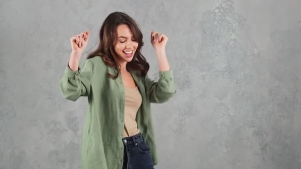 灰色のスタジオで指をスナップしながら踊る幸せな女性 — ストック動画