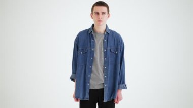 Gri atölyeye bakan, kot gömlekli duygusuz bir adam.