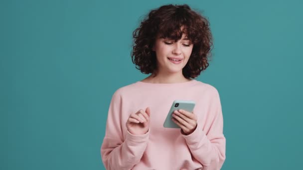 Gülümseyen Kadın Stüdyoda Elinde Tutarken Telefonda Bir Şey Yazıyor — Stok video