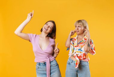 Sarı arka planda yapayalnız duran, dans eden iki güzel kız arkadaşın portresi.