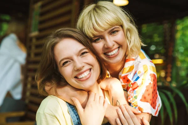 Imagen Dos Hermosas Mujeres Encantadas Riendo Abrazándose Mientras Descansan Cafetería —  Fotos de Stock