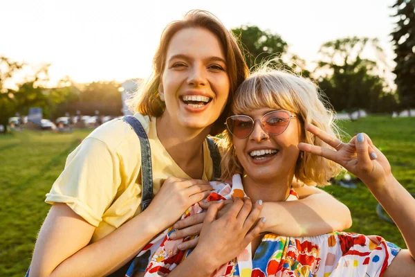 Imagen Dos Mujeres Riendo Haciendo Gestos Paz Abrazándose Mientras Caminan —  Fotos de Stock