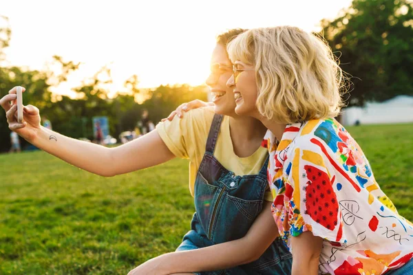 Imagen Reír Dos Mujeres Gafas Sol Tomando Selfie Teléfono Inteligente —  Fotos de Stock