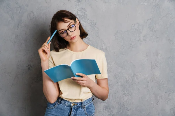 Hermosa Mujer Joven Pensativa Leyendo Libro Mientras Está Pie Aislado —  Fotos de Stock