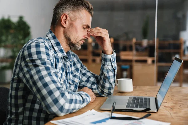 Ongelukkige Grijze Man Met Hoofdpijn Werken Met Laptop Terwijl Zitten — Stockfoto