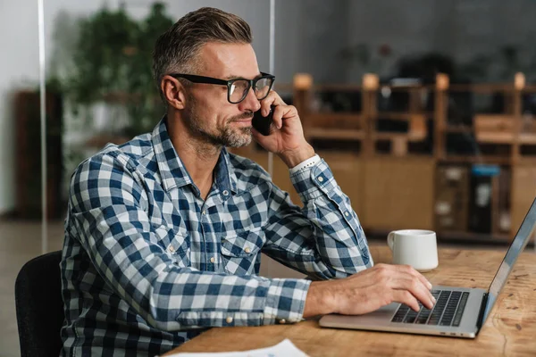 Pleased Grey Man Talking Mobile Phone While Working Laptop Office — Stock Photo, Image