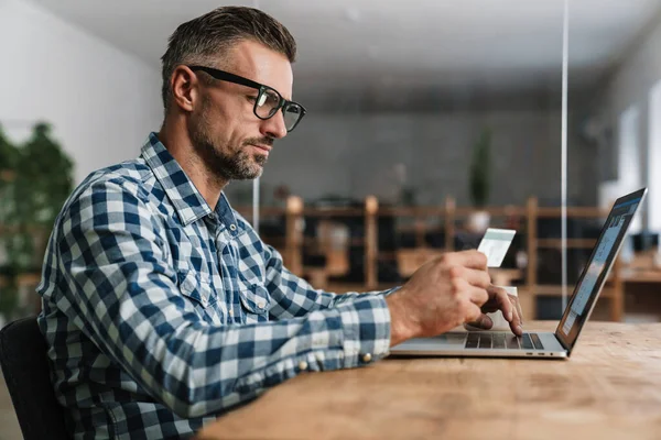 Centrado Hombre Sin Afeitar Utilizando Tarjeta Crédito Mientras Trabaja Con — Foto de Stock