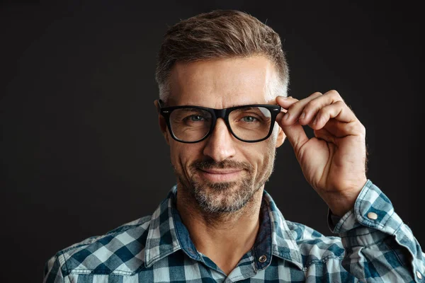 Image of a handsome grey-haired man in eyeglasses posing isolated over grey wall background