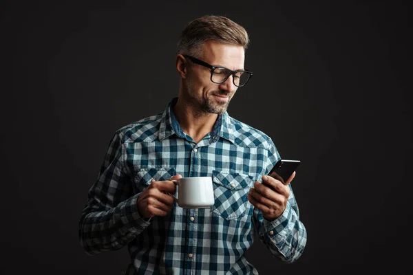 Photo Concentrated Grey Haired Man Holding Cup Coffee While Using — Stock Photo, Image