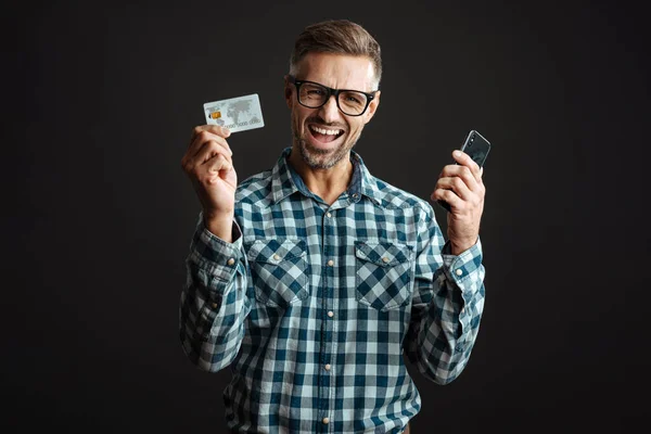 Excited Man Eyeglasses Posing Credit Card Mobile Phone Isolated Black — Stock Photo, Image