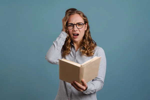 Geschokt Mooi Meisje Bril Lezen Boek Geïsoleerd Blauwe Achtergrond — Stockfoto