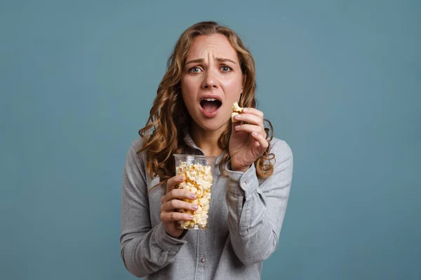 Geschokt Jonge Vrouw Kijken Het Eten Van Popcorn Geïsoleerd Blauwe — Stockfoto