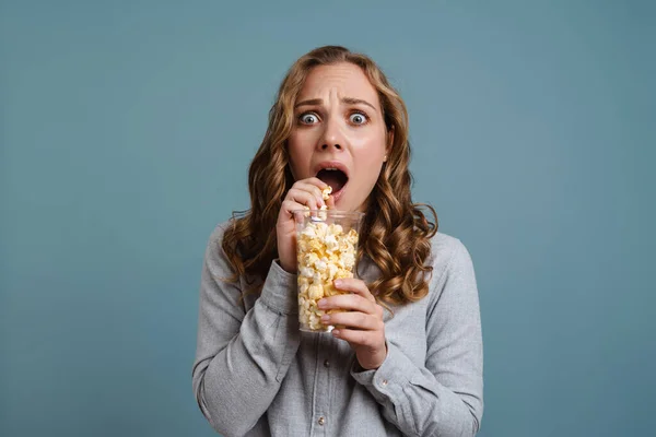 Mujer Joven Impactada Viendo Televisión Comiendo Palomitas Aisladas Sobre Fondo —  Fotos de Stock