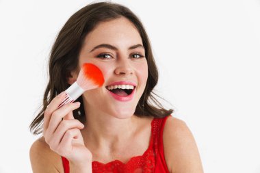 Kırmızı elbiseli, elinde makyaj fırçası olan güzel, mutlu bir kadın.