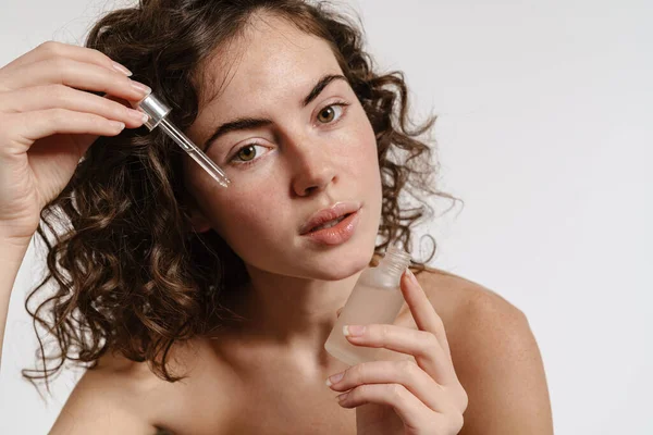 Mulher Encaracolada Semi Nua Aplicando Soro Facial Enquanto Olha Para — Fotografia de Stock