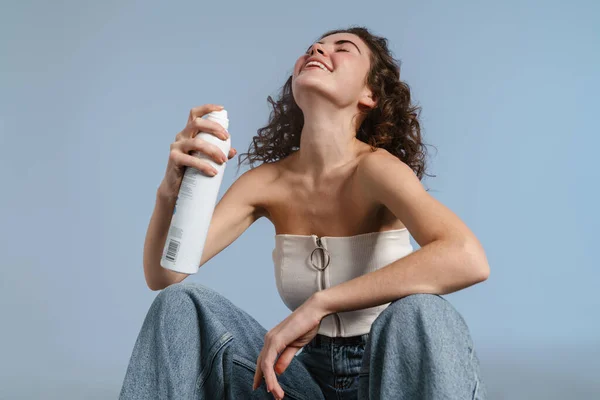 Feliz Chica Rizada Sonriendo Aplicando Agua Termal Mientras Agacha Aislado —  Fotos de Stock