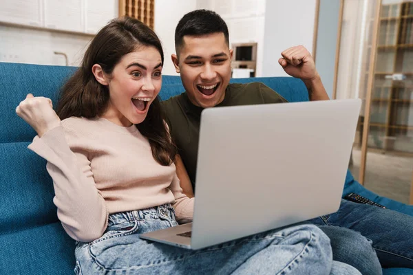 Młoda Para Relaksuje Się Kanapie Laptopem Salonie Domu Świętując Sukces — Zdjęcie stockowe