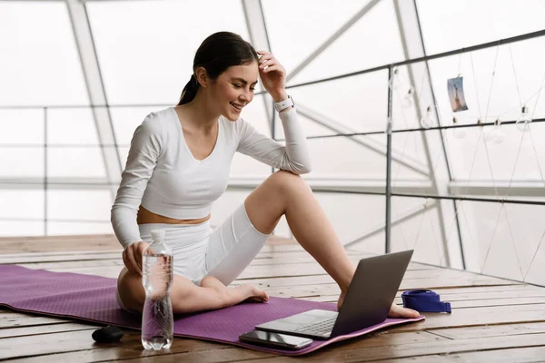 Brunett Leende Kvinna Använder Laptop Yogautövande Inomhus — Stockfoto