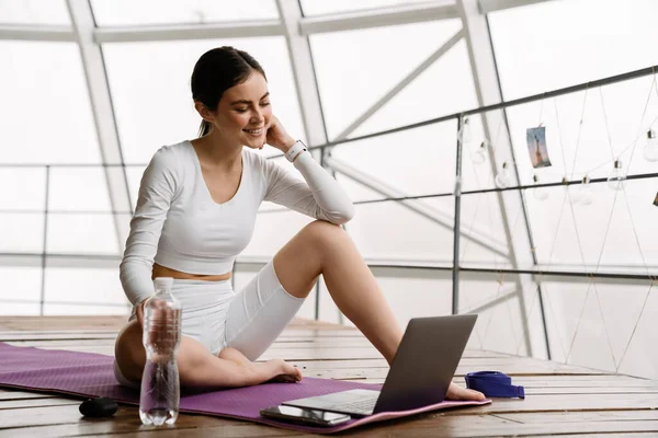 Brunett Leende Kvinna Använder Laptop Yogautövande Inomhus — Stockfoto