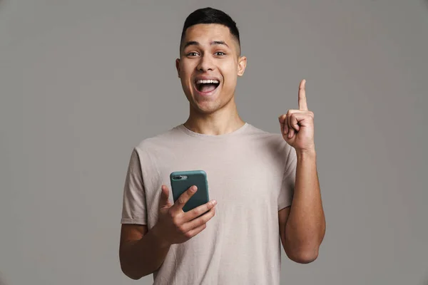 Spännande Snygg Kille Med Mobiltelefon Och Peka Finger Uppåt Isolerad — Stockfoto