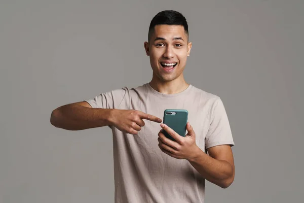 Morena Joven Excitado Hombre Sosteniendo Señalando Dedo Teléfono Móvil Aislado — Foto de Stock
