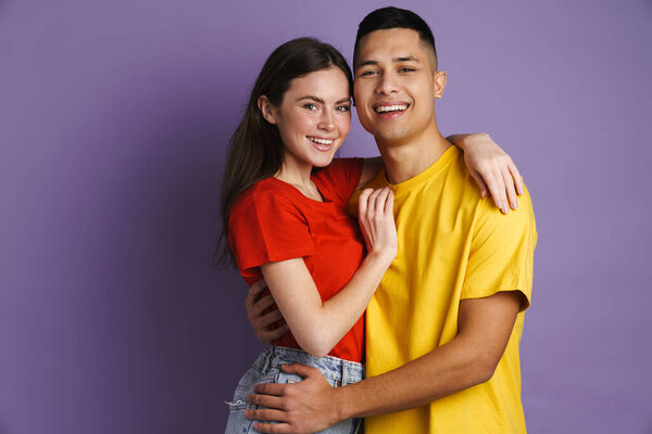 Happy beautiful couple hugging and smiling at camera isolated over violet background