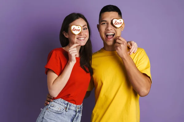 Щаслива Пара Брюнета Посміхається Поставляючи Серця Печиво Ізольоване Над Фіолетовою — стокове фото