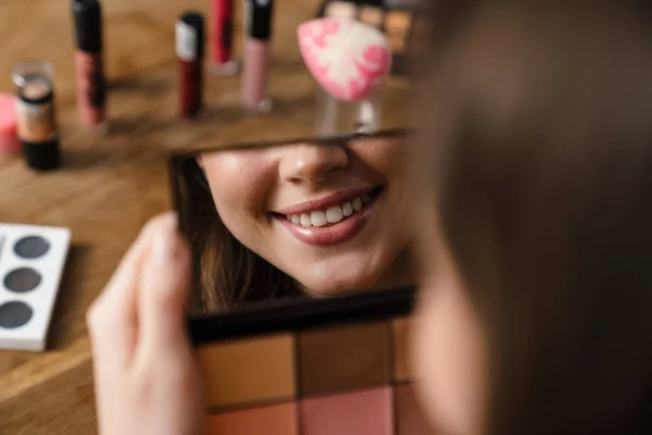 Joven Mujer Sonriente Mirando Espejo Mientras Hace Maquillaje Interiores — Foto de Stock