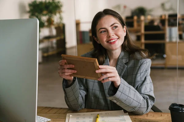 Joven Mujer Sonriente Mirando Foto Mientras Trabaja Oficina —  Fotos de Stock