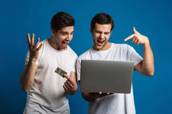 Podekscytowany Dwóch Facetów Krzyczy Podczas Pozowania Laptopem Kartą Kredytową Odizolowanych — Zdjęcie stockowe