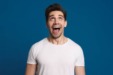 Excited unshaven guy expressing surprise on camera isolated over blue background clipart