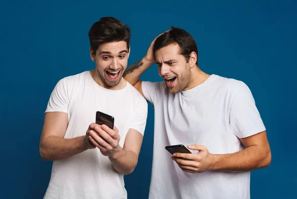 Glad Två Killar Som Uttrycker Överraskning Medan Poserar Med Smartphones — Stockfoto
